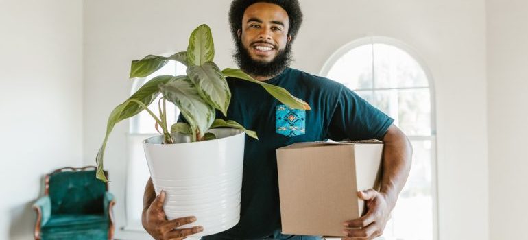 mover holding a moving box and a plant