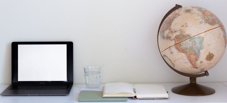 A laptop, planner and a globe