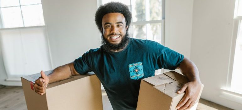 A mover holding boxes and smiling.