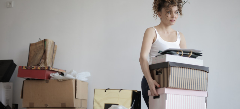 a woman carrying several shoeboxes out of the room