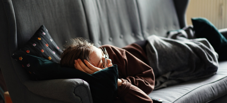 a woman lying in bed to depict one of our long distance moving advice for millennials which is not to procrastinate