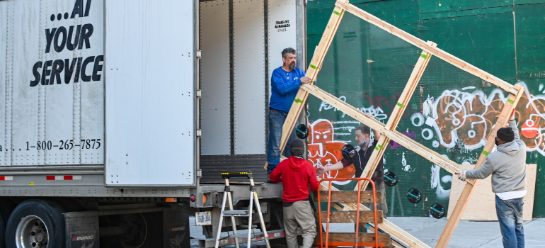 a team of movers carrying a large wooden frame into the moving truck