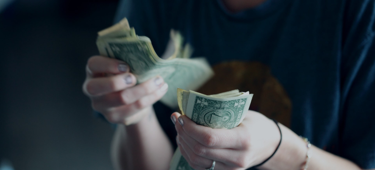 a woman counting money as one of the most important factors when moving from North Lauderdale to Miami