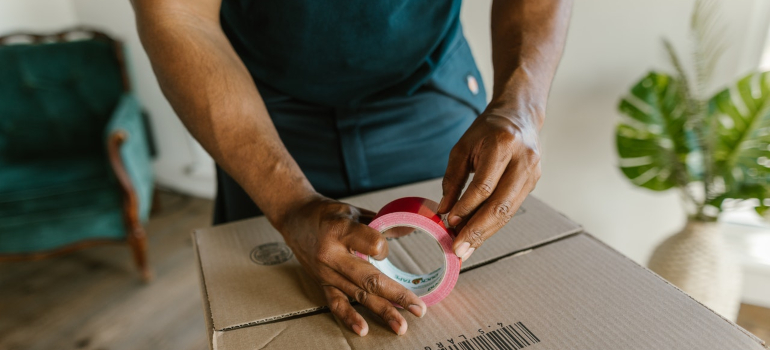 a mover applying tape on the cardboard box - best movers Orange Park FL