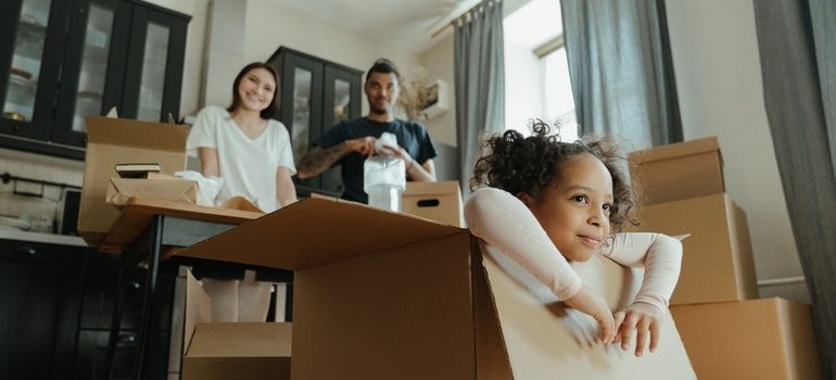 little girl an in a box and her parents waiting for residential movers Lake Worth FL