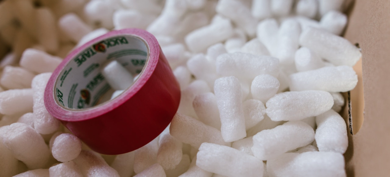 a cardboard box full of packing peanuts and a packing tape on top of it