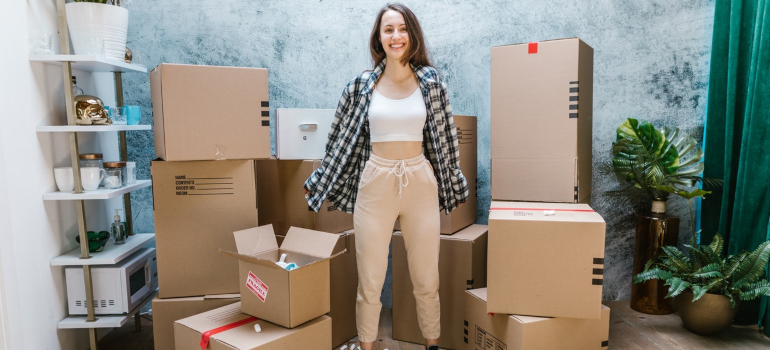 a woman standing in front of cardboard boxes after she learned how much do Florida movers charge per hour