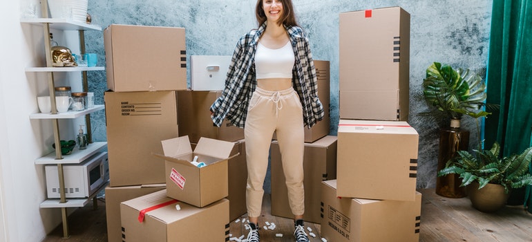 girl surrounded with moving boxes happy that she found long distance movers Parkland FL