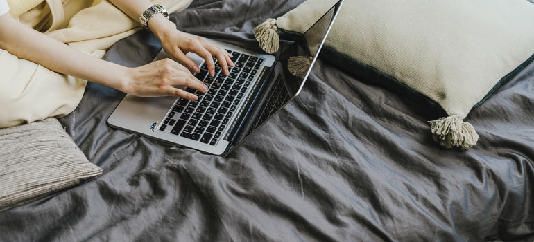 a person typing something on a laptop in bed