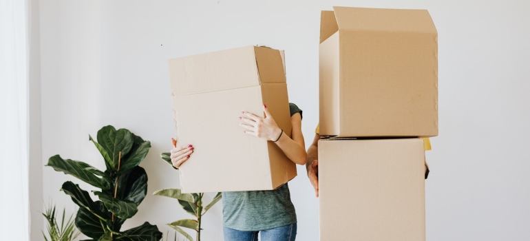 two people carrying moving boxes that cover their faces