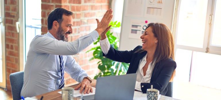 two professionals high-fiving each other in an office