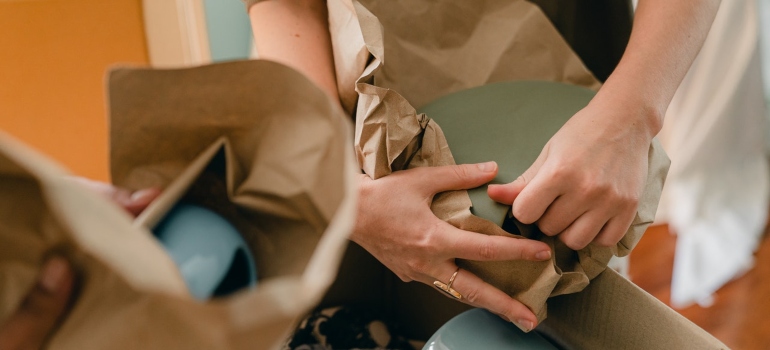 hands packing ceramics into paper