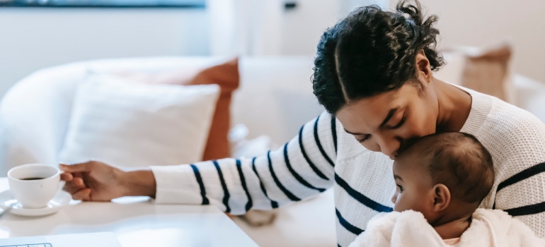 a mother kissing her baby by the working desk