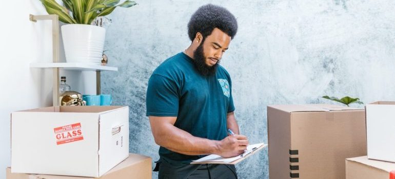 a man in blue t-shirt writing something surrounded by boxes