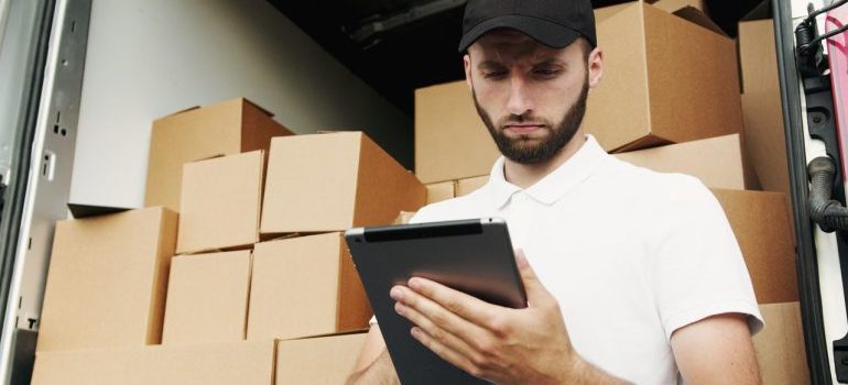 commercial movers Key West FL looking at a tablet in front of a truck with moving boxes