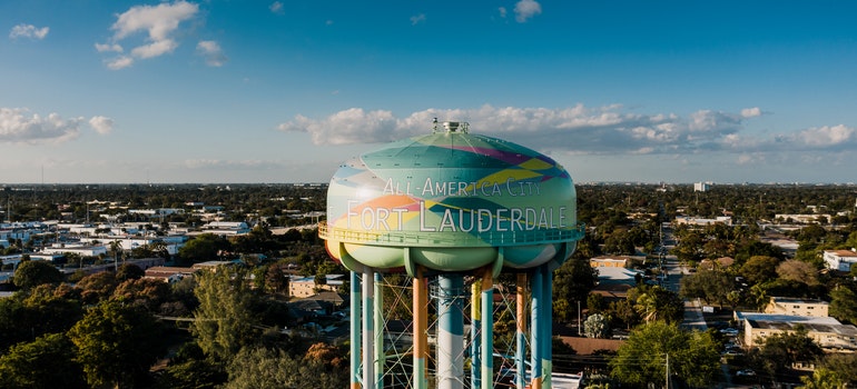 Cityscape with residential buildings between lush trees and tall water tower - Florida cities for renters.