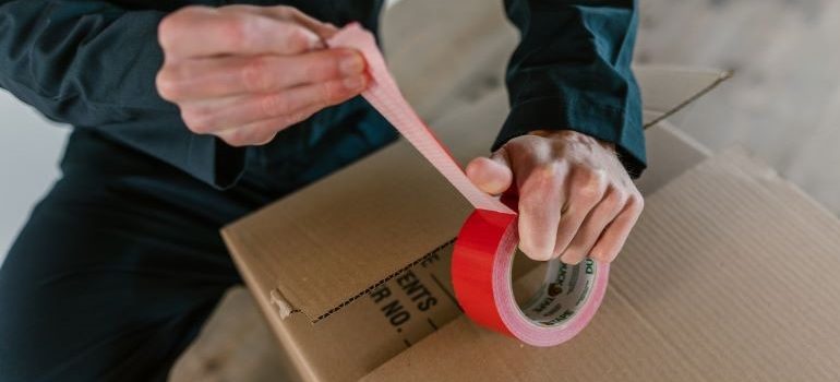 Local movers Pinellas Park FL putting a tape on a moving box