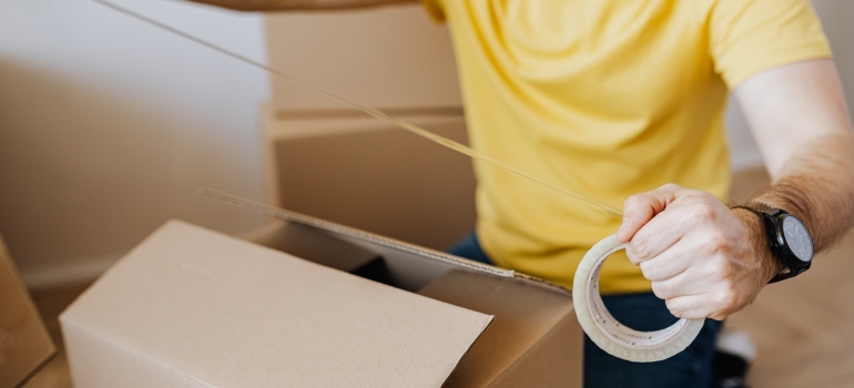 a person putting tape on a cardboard box