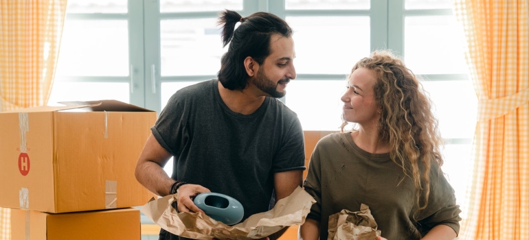 two people talking and smiling while packing items in cardboard boxes