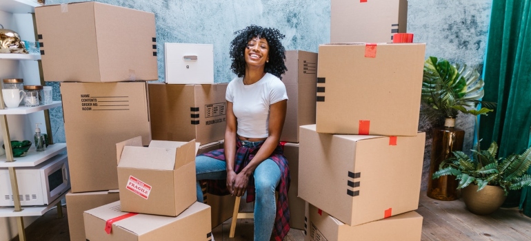 a woman sitting happily among cardboard boxes