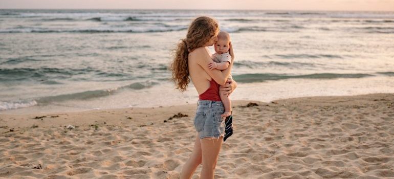 Woman with baby on the beach which is another reason why people move to Florida