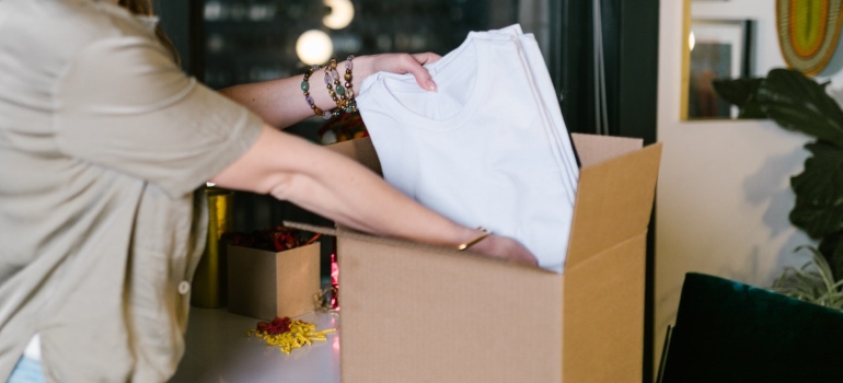 a person packing shirts into a cardboard box