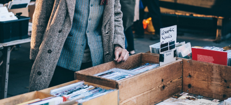 Person standing in front of a brown wooden crate filled with graphic novels