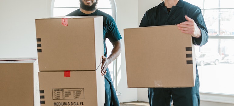 Two movers holding cardboard boxes