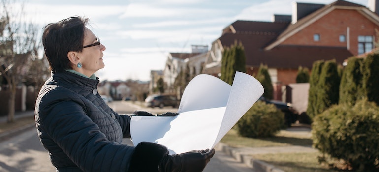 A woman holding a paper in front of a house