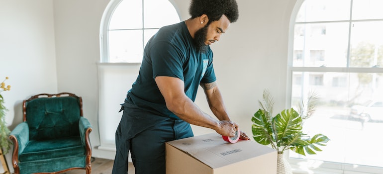 a man in green working suit putting a tape on the box