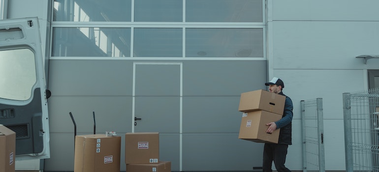 Man Walking while Carrying Brown Cardboard Boxes.