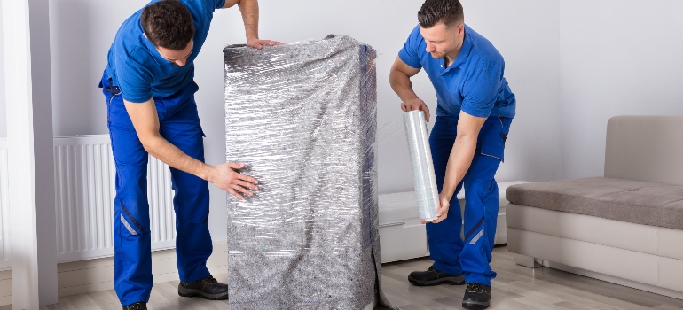 Two Young Male Movers Packing Furniture In Living Room - Local movers White Springs.