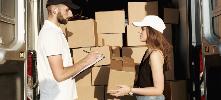 a man writing down notes and a woman holding a box