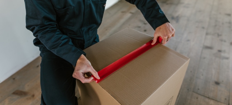 a man sealing a cardboard box with a duct tape
