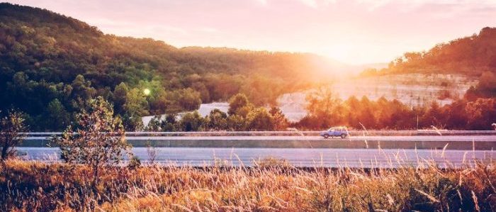 Car on a highway while the sun is setting in the back ground.