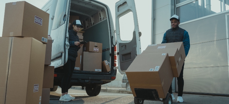 Movers using a dolly for carrying boxes