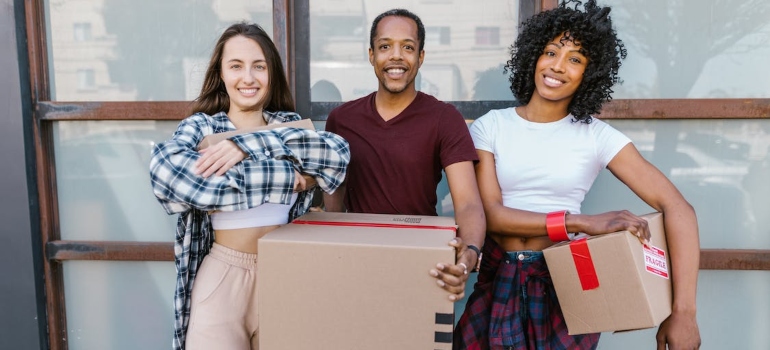 three persons holding boxes