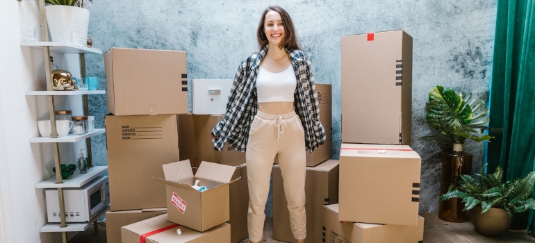 a girl happy to have found the best movers Port Orange FL standing among a pile of moving boxes 