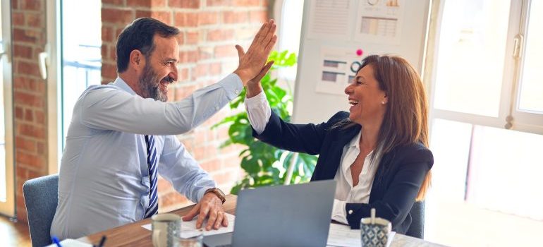 Business man and woman doing high five after finding the best commercial movers Deltona FL