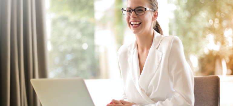 Laughing businesswoman working in office with laptop
