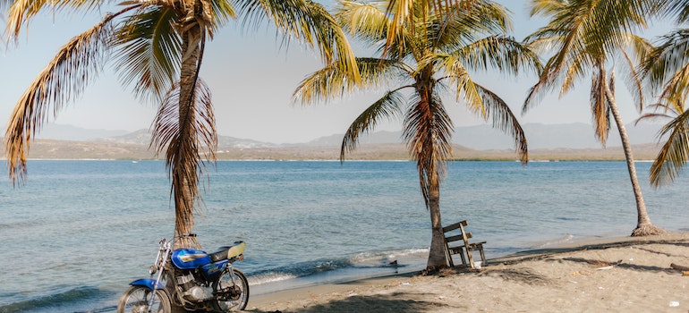 Tropical sandy beach with motorbike and palms
