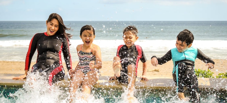 three kids and a woman playing with water at the beach