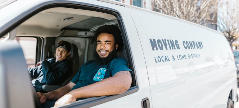 Two workers from a moving company in a moving van