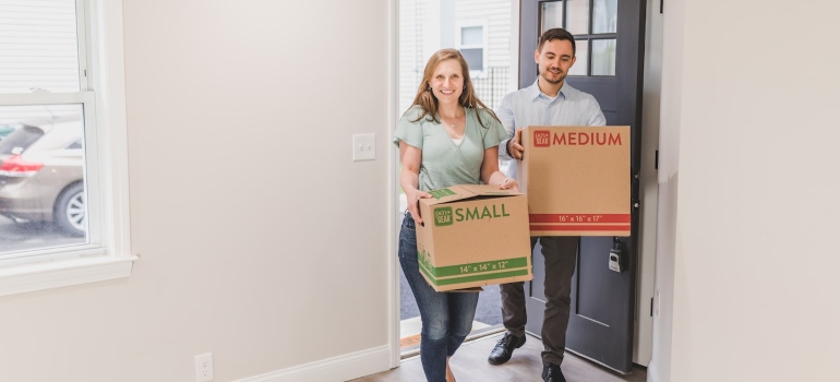 Two people holding boxes at the door