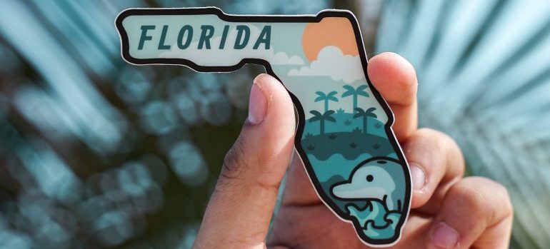 Person holding a small sign of Florida