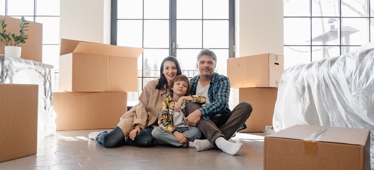 a family sitting next to the moving boxes 