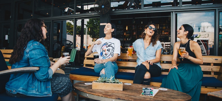 Four women chatting and laughing while sitting on bench