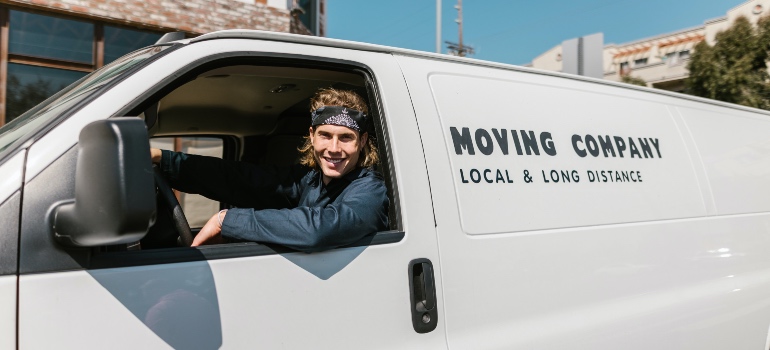 A moving company employee smiling in a white van