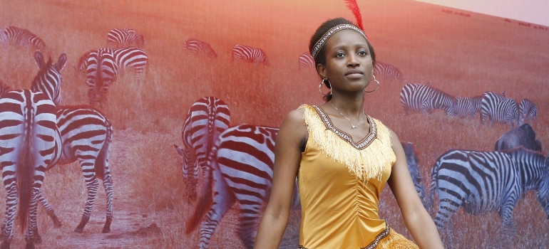 African model stands in front of a picture of a prairie with zebras
