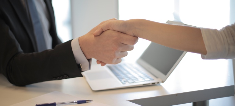 A person in a black suit shaking hands with an employee